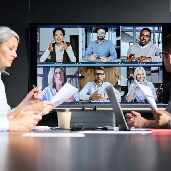Pantalla de sala de reuniones con una videollamada de ocho personas