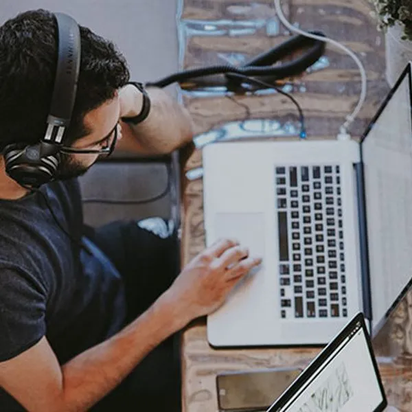Un hombre con auriculares trabaja con un portátil, visto desde arriba