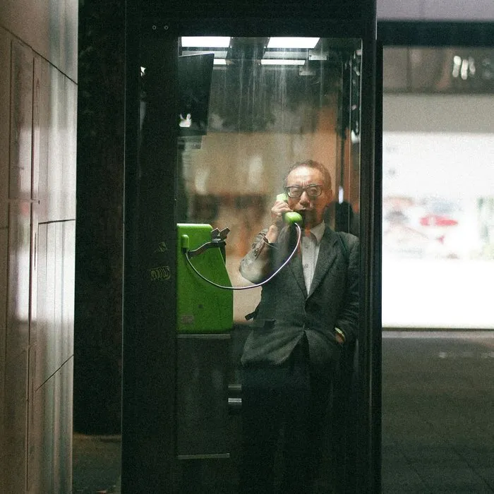 Un hombre con traje hablando por teléfono en una cabina de cristal